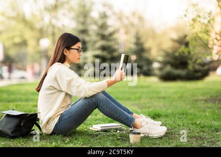 Mädchen liest ein Buch sitzen im Park, Copyspace Stockfoto