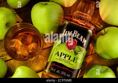 Stillleben mit einer Flasche Jim Beam Apple Bourbon , Likör aus Kentucky , mit einem Glas kalten Whiskey auf Eis auf einem hölzernen braunen Hintergrund Stockfoto