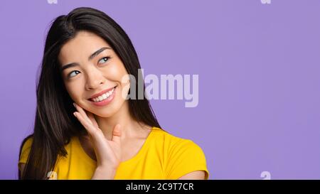 Interessantes Angebot. Nachdenkliche Asiatische Mädchen Blick Auf Kopie Raum Über Lila Hintergrund Stockfoto