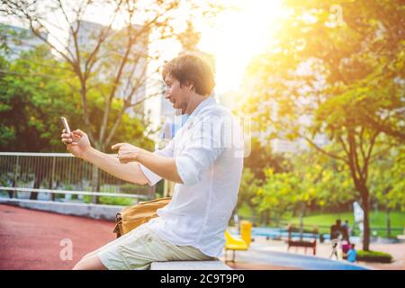 Junger Mann am Telefon. Dressing in einem weißen Hemd, beige Shorts. Mobile Office-Konzept Stockfoto