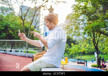 Junger Mann am Telefon. Dressing in einem weißen Hemd, beige Shorts. Mobile Office-Konzept Stockfoto
