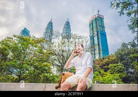 Junger Mann am Telefon. Dressing in einem weißen Hemd, beige Shorts. Mobile Office-Konzept Stockfoto