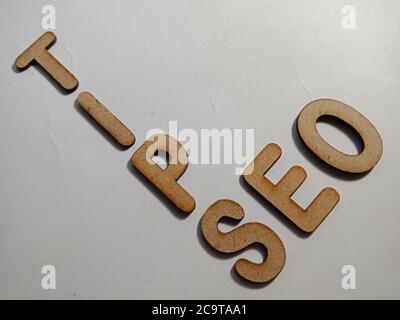 SEO Suchmaschinen-Optimierung Tipps Konzept Wort auf weißer Oberfläche mit Holzkreuz Text Wolke Rahmen Kunst Geschäft Lernen Hintergrund vorgestellt. Stockfoto