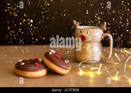 Weihnachts-Frühstückstisch mit Schokolade Donuts dekoriert rot und weiß bestreut mit heißem Kakao in Hirschbecher Stockfoto