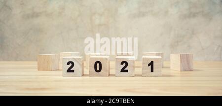 2021 frohes neues Jahr auf Holzblock auf Holztisch und grauem Hintergrund. Neujahr Konzept. Stockfoto