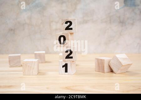2021 frohes neues Jahr auf Holzblock auf Holztisch und grauem Hintergrund. Neujahr Konzept. Stockfoto