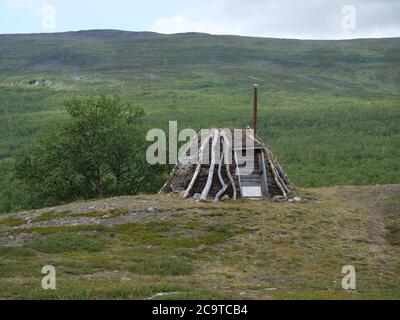 Abadoned Sami Hütte Goathi in grünen Hügeln Landschaft des Abisko National Park. Goahti ist lappische traditionelle Behausung aus Stoff, Torfmoos und Timb Stockfoto