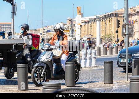Junge Frau, die im geschäftigen Verkehr in Marseille, Frankreich, mit dem Moped unterwegs ist Stockfoto