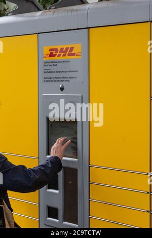 DHL Packstation, wo Kunden ihre Bestellung selbst abholen und auch Pakete versenden können. Hier erfahren Sie, wie ein Kunde die PIN eingibt Stockfoto