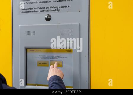 DHL Packstation, wo Kunden ihre Bestellung selbst abholen und auch Pakete versenden können. Hier erfahren Sie, wie ein Kunde den Vorgang abschließt Stockfoto