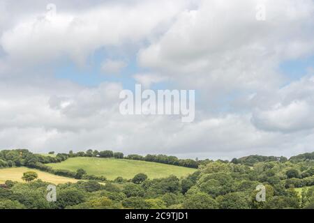 Etwas bedrohlich aussehende dunkle Wolkenformation siedelte über einem entfernten Hangfeld / Ackerland in Großbritannien. Sammeln von Sturmwolken, Wolke Silber Futter. Stockfoto