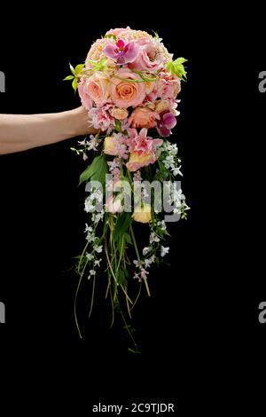 Schöne stilvolle Hochzeit Blumenstrauß in einer Hand der Frau auf schwarzem Hintergrund. Stockfoto