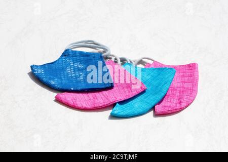 Blaue und rote Mund- und Nasenmasken nebeneinander auf einem weißen Tisch angeordnet Stockfoto