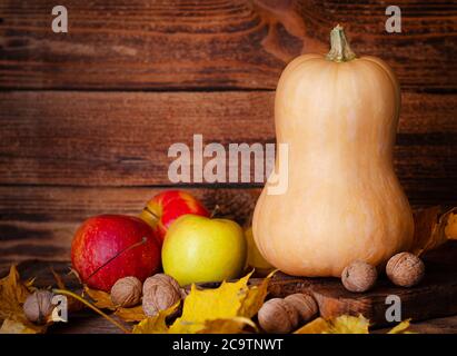 Kürbis, Apfel und Walnüsse auf rustikalen Holzmöbeln Hintergrund mit Platz für Text. Danksagung und Ernte Stockfoto