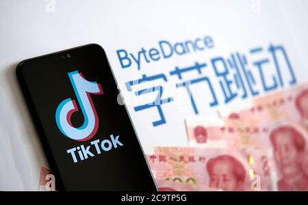 Stone / UK - 2. August 2020: TikTok App Logo auf dem Bildschirm und Bytedance Company Logo mit chinesischem Geld auf dem verschwommenen Hintergrund. Selektiver Fokus. Stockfoto