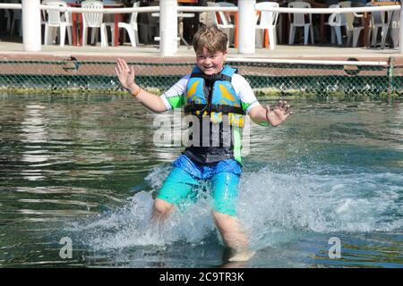 WEISSER JUNGE IM ALTER VON 10 JAHREN BEIM SCHWIMMEN MIT EINEM DELFIN IN MEXIKO Stockfoto