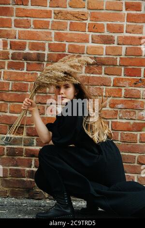 Porträt der kauernden jungen Frau in langen schwarzen Kleid und schweren Armee Stiefel Stockfoto