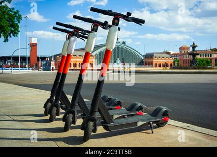 Elektro-Scooter zur Miete in Madrid, Spanien. Im Hintergrund der Bahnhof Atocha. Stockfoto