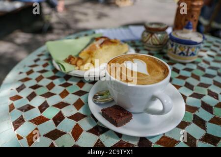 Weiße Keramik Tasse Cappuccino auf der Oberseite mit schönen zarten Latte Kunst mit Herz-Muster, auf Outdoor-Keramik Fliesen Tisch. Stockfoto