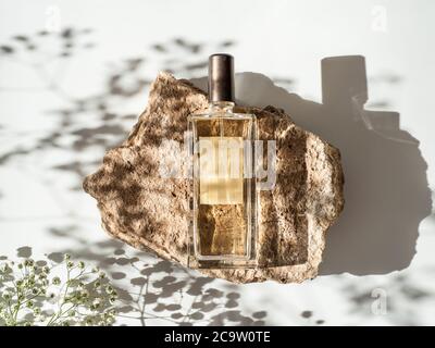 Mockup geometrische Form Stein Podium mit Glas Parfüm Flasche Draufsicht. Steinform mit Gypsophila-Blüten Schattierungen auf weißem Hintergrund. Flach liegend. Kann als Parfüm und kosmetische Nachbau verwenden Stockfoto