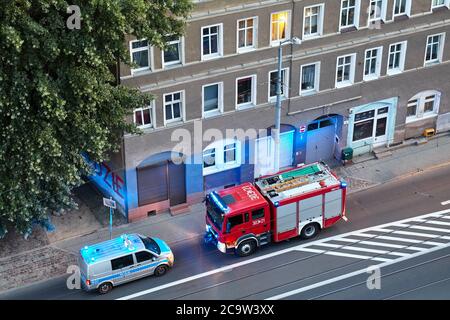 Szczecin, Polen - 01. August 2020: Feuerwehrauto und Polizeiwagen reagieren auf einen Notfall im Mietshaus in der Niemierzynska Straße in der Abenddämmerung. Stockfoto