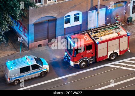 Szczecin, Polen - 01. August 2020: Feuerwehrauto und Polizeiwagen reagieren auf einen Notfall im Mietshaus in der Niemierzynska Straße in der Abenddämmerung. Stockfoto