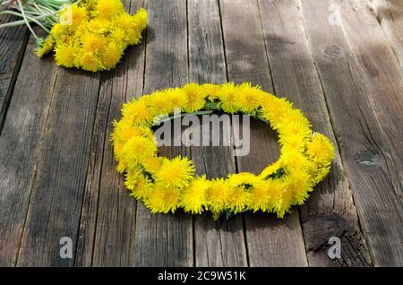Löwenzahnkranz auf dem Holztisch, im Freien Stockfoto