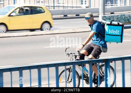 Belgrad, Serbien - 31. Juli 2020: Ein Mann, der für den Lebensmittellieferdienst Wolt arbeitet, fährt mit dem Fahrrad in der Fahrradspur auf der Stadtstraßenbrücke Stockfoto