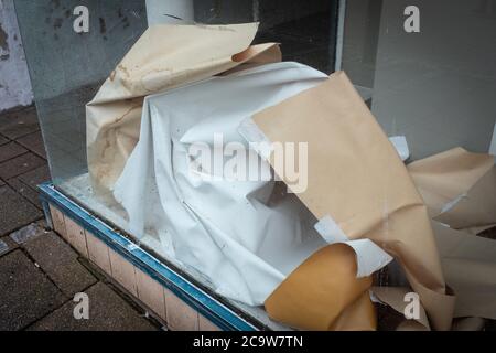 Nahaufnahme eines leeren Ladens in Dumfries, Schottland, mit einem zerknitterten Papier darin. Aufgrund der wirtschaftlichen Rezession geschlossen. Stockfoto