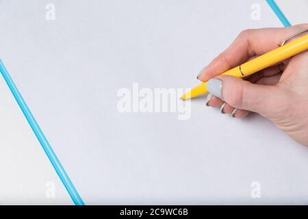 Weibliche Hand mit Stift auf einem leeren Blatt Papier. Frau legt Unterschrift auf Papier. Nahaufnahme. Stockfoto
