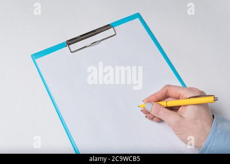 Weibliche Hand mit Stift auf einem leeren Blatt Papier. Frau legt Unterschrift auf Papier. Nahaufnahme. Stockfoto