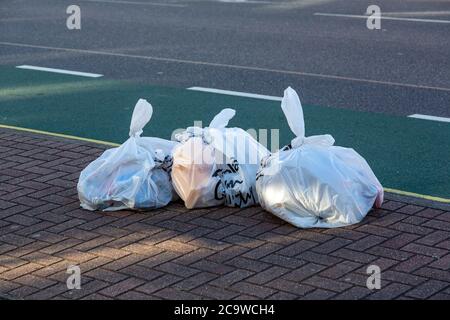 Weiße Müllsäcke oder Müllsäcke auf der Straße bereit zur Abholung Stockfoto