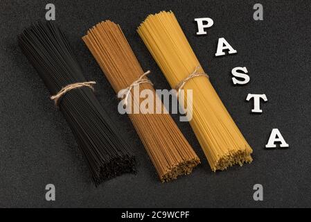 Drei Arten von Spaghetti auf grauem Hintergrund und Wort Pasta. Italienische Küche Stockfoto