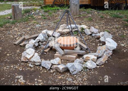 Ein alter Retro-Terrakotta-Kochtopf hängt an einem Haken über einem Lagerfeuer ohne Feuer. Zubereitung von Lebensmitteln in Natur oder Wald Konzept. Stockfoto