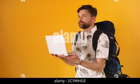 Junger Mann mit Rucksack, Kamera haltend und verloren aussehend. Navigation mit modernen Geräten Konzept. Hochwertige Fotos Stockfoto