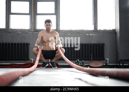 Athletischen jungen Mann mit Schlacht Seil, Übung in Functional Training Fitness Gym. Stockfoto