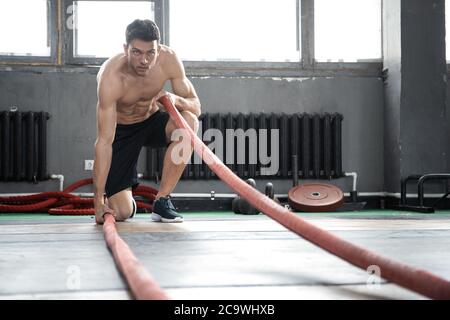 Athletischen jungen Mann mit Schlacht Seil, Übung in Functional Training Fitness Gym. Stockfoto