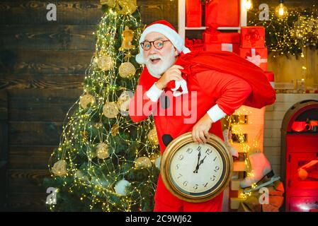 Frohes neues Jahr. Weihnachtszeit. Es ist fast zwölf Uhr. Santa machen lustige Gesicht und halten Uhr zeigt fünf Minuten bis Mitternacht. Fünf Minuten bis zu Neu Stockfoto