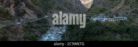 Panorama des nepalesischen Bergdorfes durch eine Hängebrücke über das Tal der Schlucht des Flusses Marshyangdi, Annapurna-Rundkurs, Himalaya, Nepal, Asien Stockfoto