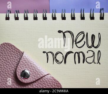Neue normale Wörter in Copybook und Brieftasche. Wort nach Coronavirus. Soziales und Geschäftskonzept. Stockfoto