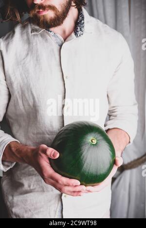 Bärtiger Mann hält ganze Wassermelone Stockfoto