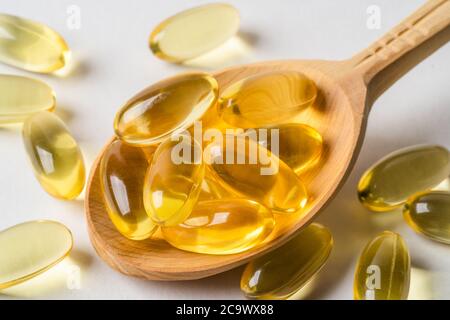 Omega 3 gelbe Kapseln in Holzlöffel auf weißem Hintergrund. EPA und DHA sind zwei Arten von Omega-3-Fettsäuren essentielle Fettsäuren. Stockfoto