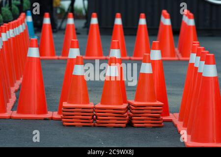 leuchtend orange Leitkegel stehen in einer Reihe auf dunklem asphalt Stockfoto