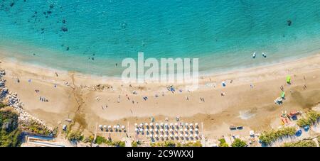 Luftbild von oben Panorama des schönen Coral Strand in Paphos mit azurblauem Meerwasser, Zypern. Sandküste mit Sonnenschirmen, Liegen, Menschen und klarem Meerwasser. Stockfoto