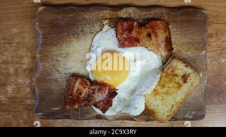 Foto Draufsicht auf Spiegeleier mit frittierten Stücken Speck und Croutons Stockfoto