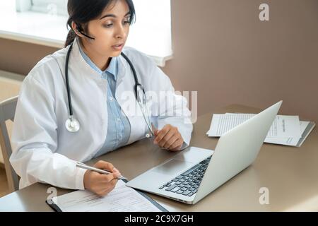 Indischer Telemedizin Arzt trägt Headset Gespräch mit dem Patienten per Online-Videoanruf. Stockfoto