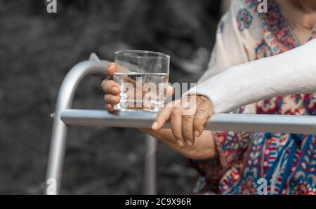 Ältere Frau gebrochenes Handgelenk mit Wanderer im Hinterhof. Stockfoto