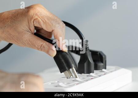 Schließen Sie ältere Hände an die Steckdose an Stockfoto