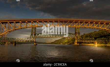 Sonnenuntergang über der Second Narrows Bridge (Ironworkers Bridge) des Trans Canada Highway und einer Eisenbahnbrücke, über Burrard Inlet und Vancouver Harbour Stockfoto