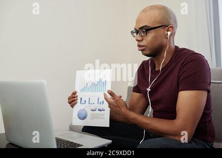 Seriöser junger Projektmanager, der Finanzbericht bei einem Online-Meeting mit Kollegen vorstellt Stockfoto